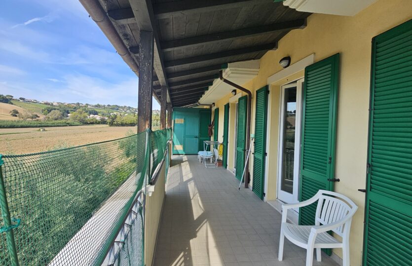 Terrazza lungo la facciata con persiane verdi, complesso Le File
