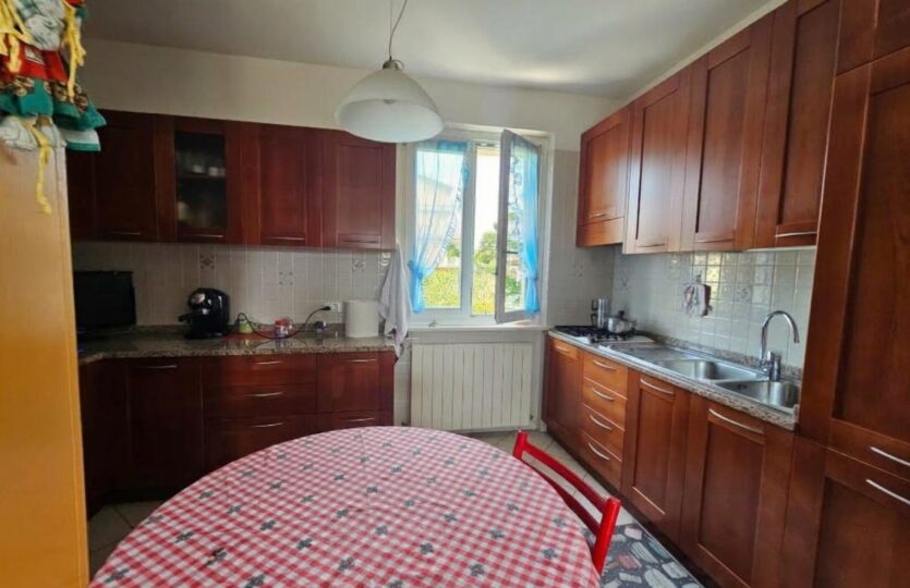 Cucina con mobili in legno e tavolo con tovaglia rossa