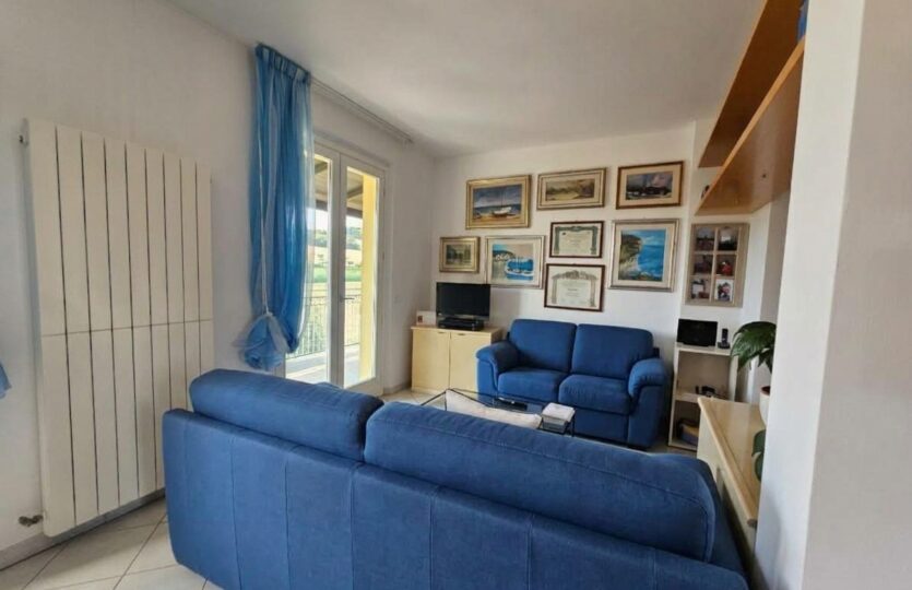 Angolo del soggiorno con divano blu e quadri alle pareti